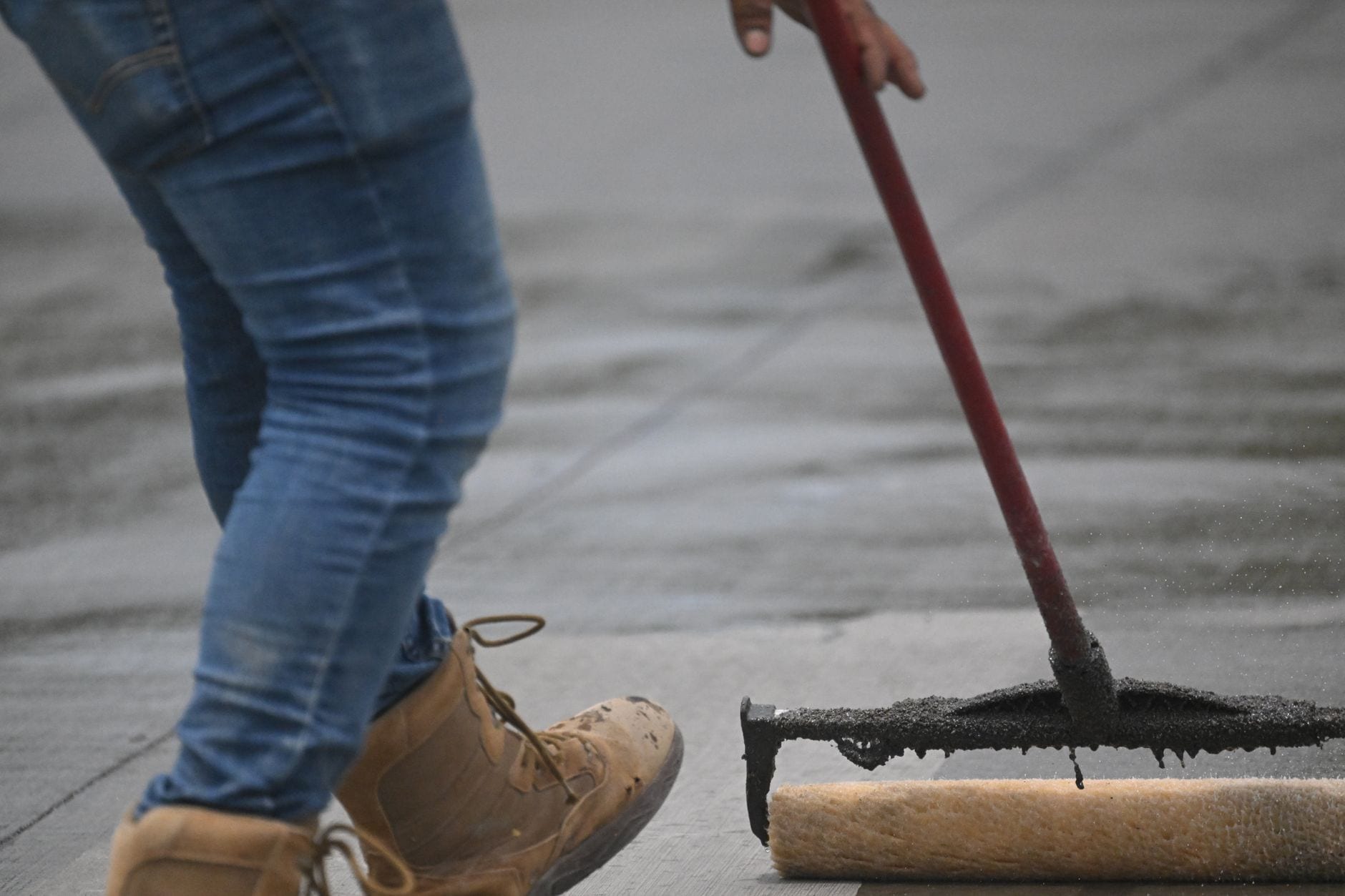 A sealer being spread across a concrete surface.